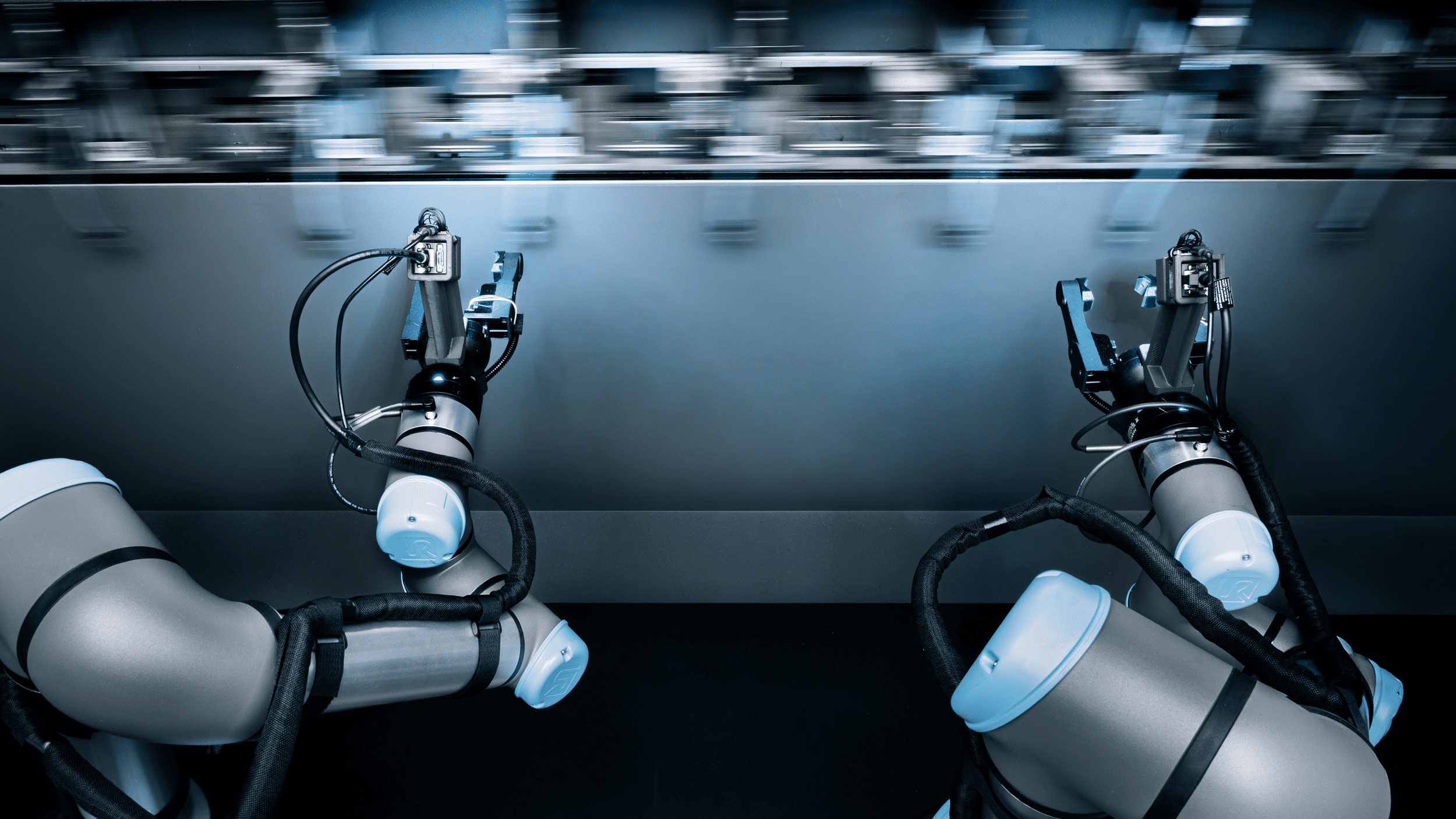 Two robotic arms equipped with precision tools work on a high-tech assembly line, surrounded by mechanical components, illustrating advanced automation and manufacturing processes.